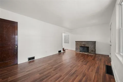 a view of empty room with wooden floor and fireplace