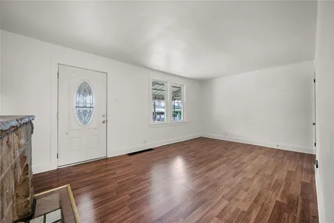 an empty room with wooden floor cabinet and window