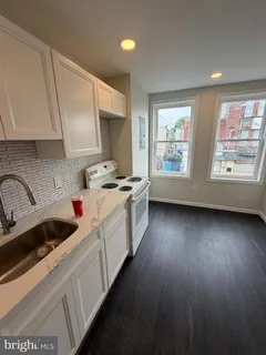 a kitchen that has a lot of white cabinets and wooden floor