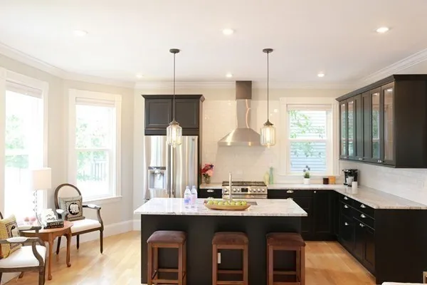 a room with stainless steel appliances kitchen island granite countertop a table chairs in it and a window