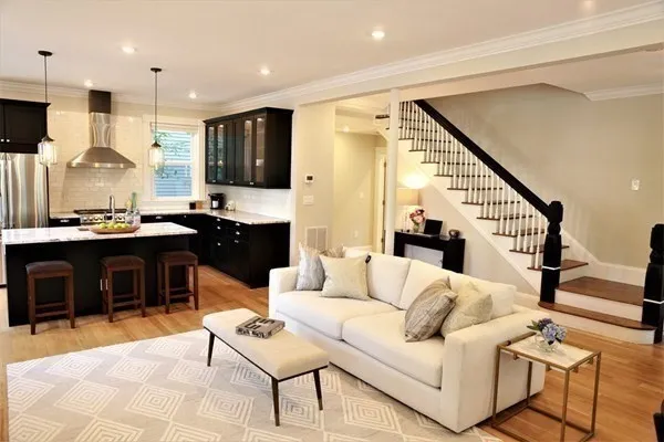 a living room with furniture kitchen view and a wooden floor