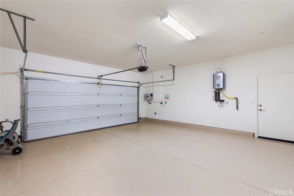 38121 Summer Ridge Drive Murrieta, CA 92563 - Photo 26 of 30 Fully Drywalled Two Car Garage with Epoxy Floors, showing the Solar System Inverter, the Sprinkler System Control Panel, the Tankless WH and the Garage Service Door to the SideYard.
