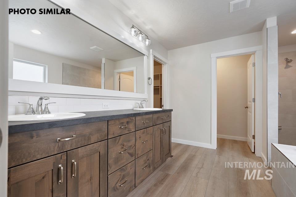1645 Haystack Emmett, ID 83617 - Photo 16 of 33 Dual vanity with wood-finish cabinetry and brushed nickel hardware, set against a white subway tile backsplash