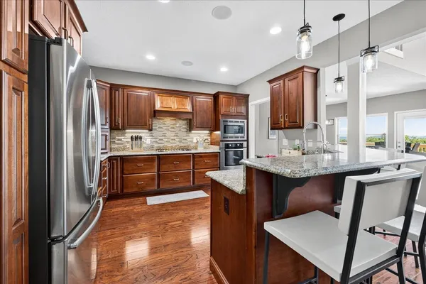 an open kitchen with wooden floor and stainless steel appliances