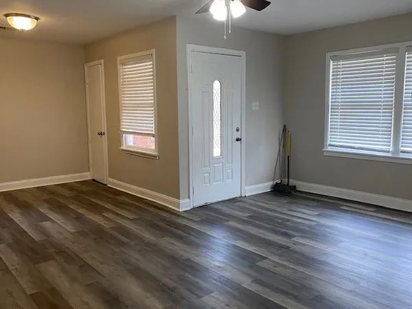 an empty room with wooden floor and windows