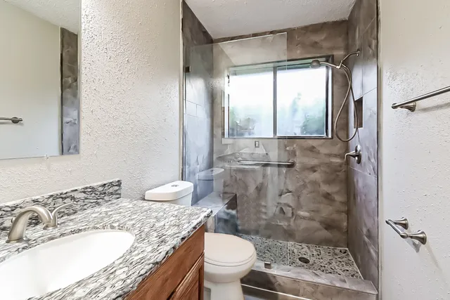 a bathroom with a granite countertop sink toilet and shower