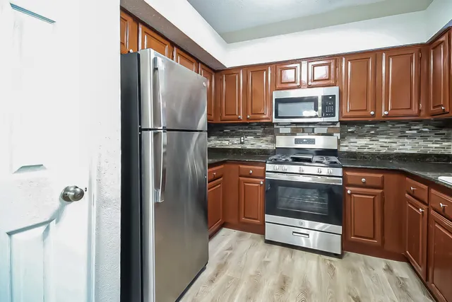 a kitchen with stainless steel appliances granite countertop a refrigerator stove and sink