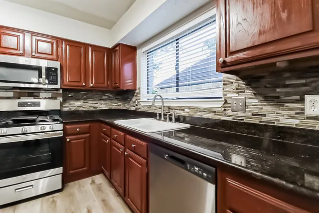 a kitchen with stainless steel appliances granite countertop a sink stove and microwave
