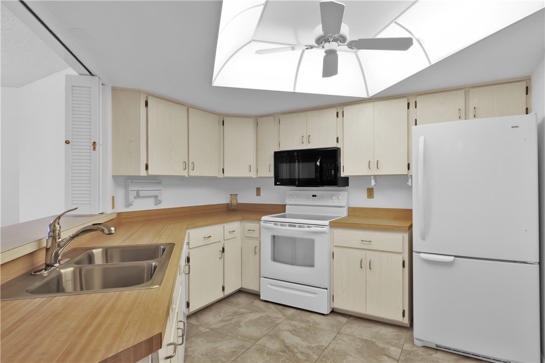1850 Bay Road, Unit 2C Vero Beach, FL 32963 - Photo 12 of 36 a kitchen with a sink a stove and refrigerator