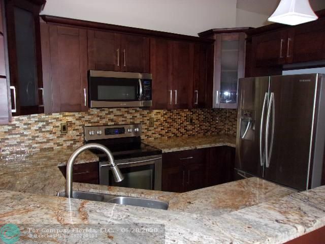 1564 Sunset Way Weston, FL 33327 - Photo 2 of 40 a kitchen with granite countertop a refrigerator stove and microwave
