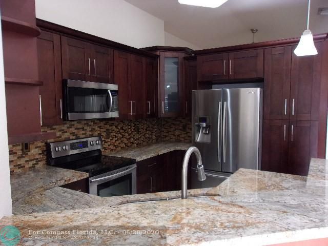 1564 Sunset Way Weston, FL 33327 - Photo 33 of 40 a kitchen with granite countertop wooden cabinets a refrigerator and a sink