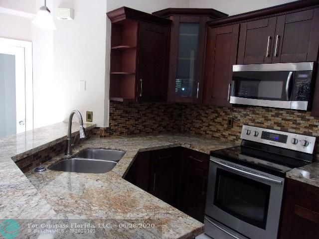 1564 Sunset Way Weston, FL 33327 - Photo 35 of 40 a kitchen with granite countertop a sink and a stove top oven with granite countertops