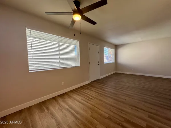 a view of an empty room with wooden floor and a window