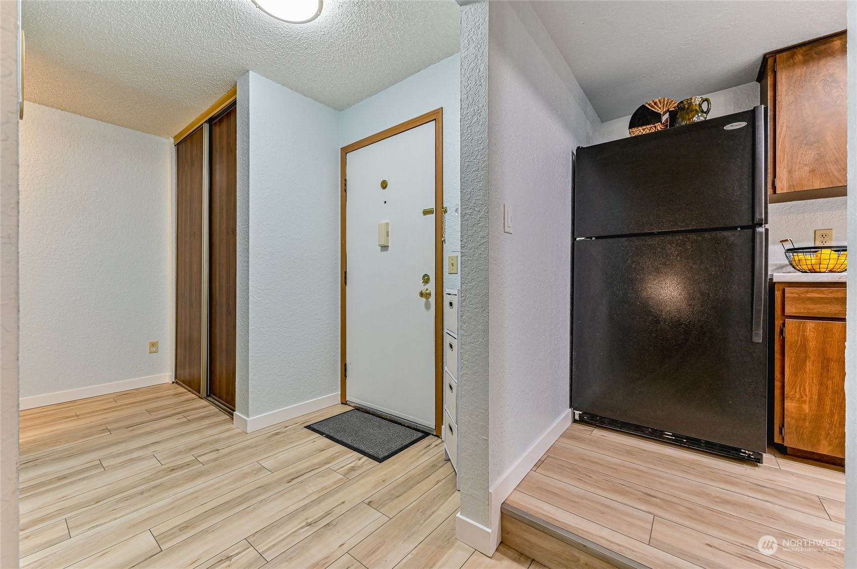14401 Southeast Petrovitsky Road, Unit E105 Renton, WA 98058 - Photo 15 of 38 a view of a refrigerator in kitchen and an empty room with wooden floor windows