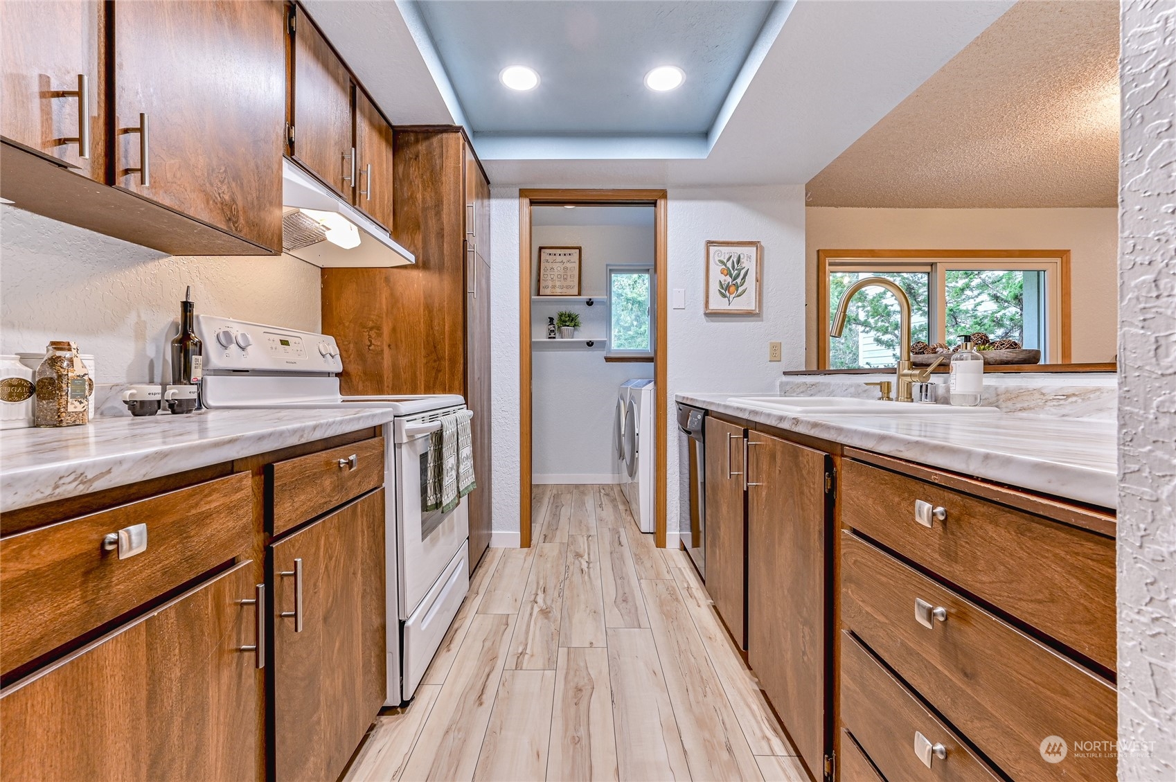 14401 Southeast Petrovitsky Road, Unit E105 Renton, WA 98058 - Photo 3 of 38 a kitchen with stainless steel appliances sink stove microwave and wooden floor
