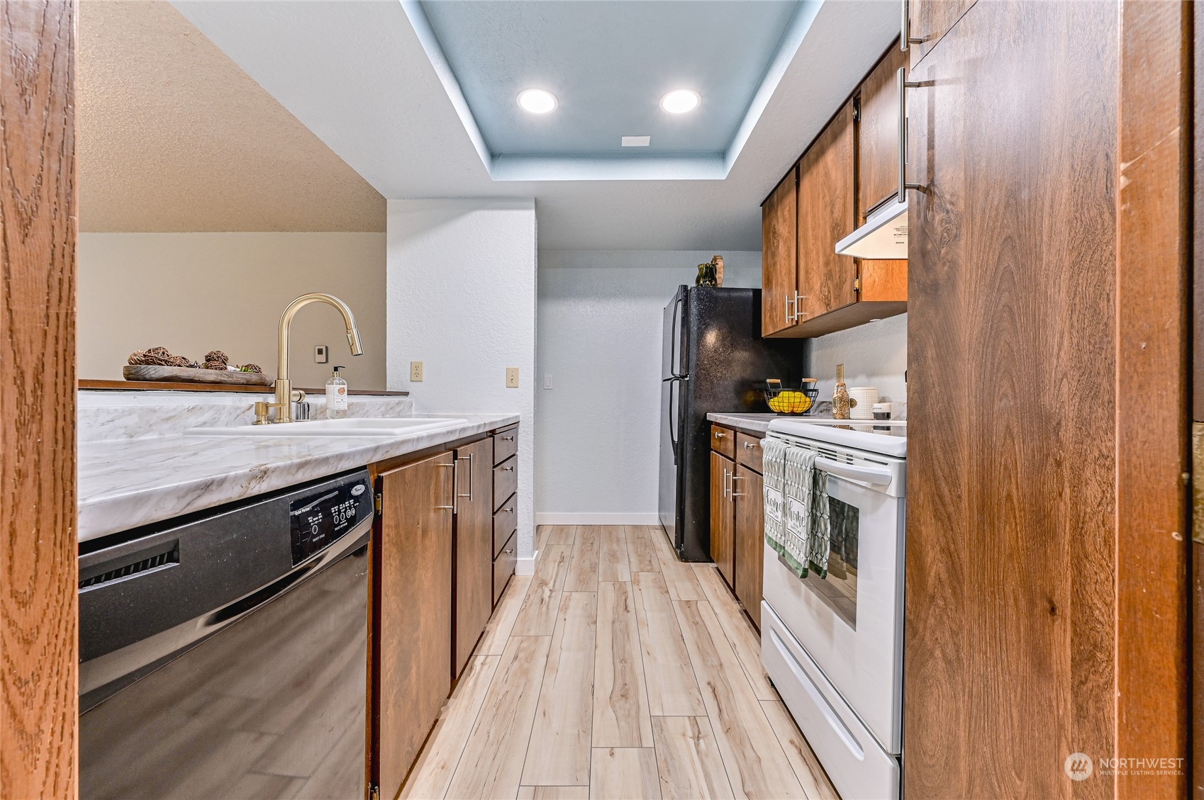 14401 Southeast Petrovitsky Road, Unit E105 Renton, WA 98058 - Photo 7 of 38 a kitchen with a sink a stove top oven and cabinetry