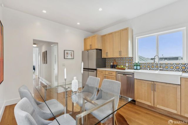 a kitchen with stainless steel appliances granite countertop a table chairs and a refrigerator