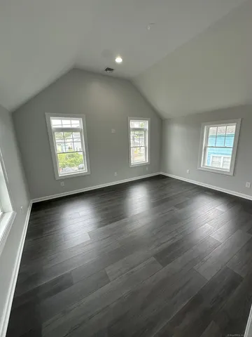 a view of an empty room with wooden floor and window