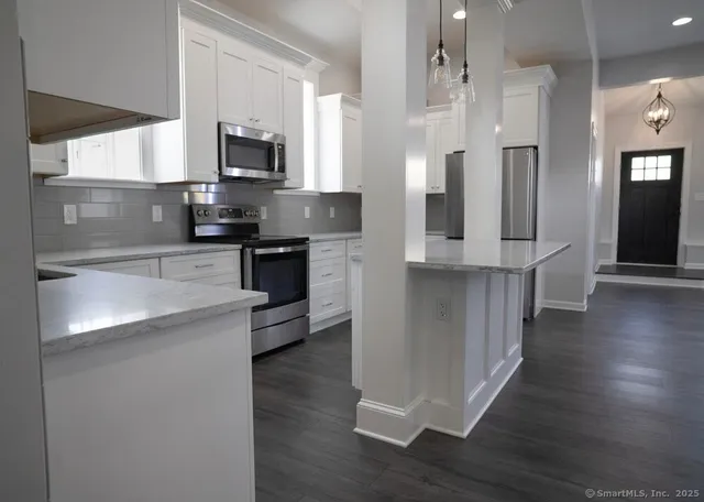 a kitchen with stainless steel appliances granite countertop a refrigerator a stove top oven a sink dishwasher and wooden floor