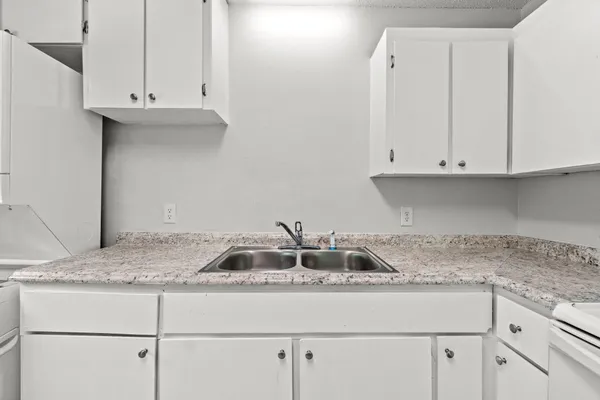 a kitchen with granite countertop white cabinets and a white appliances