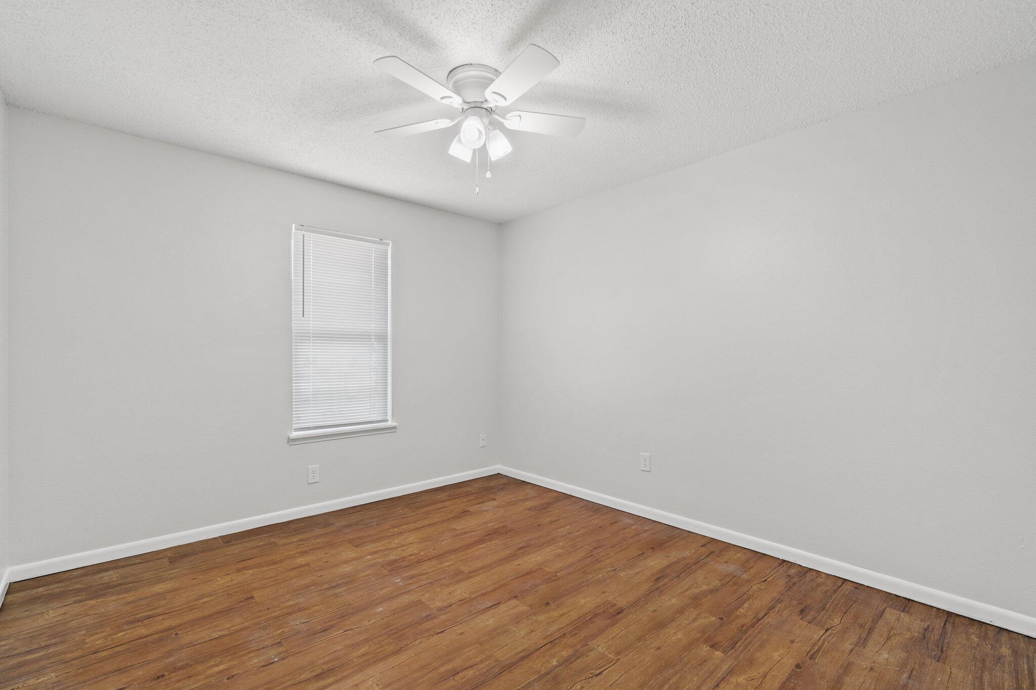248 4 Mile Road, Unit G Freeport, FL 32439 - Photo 12 of 19 an empty room with wooden floor and a ceiling fan