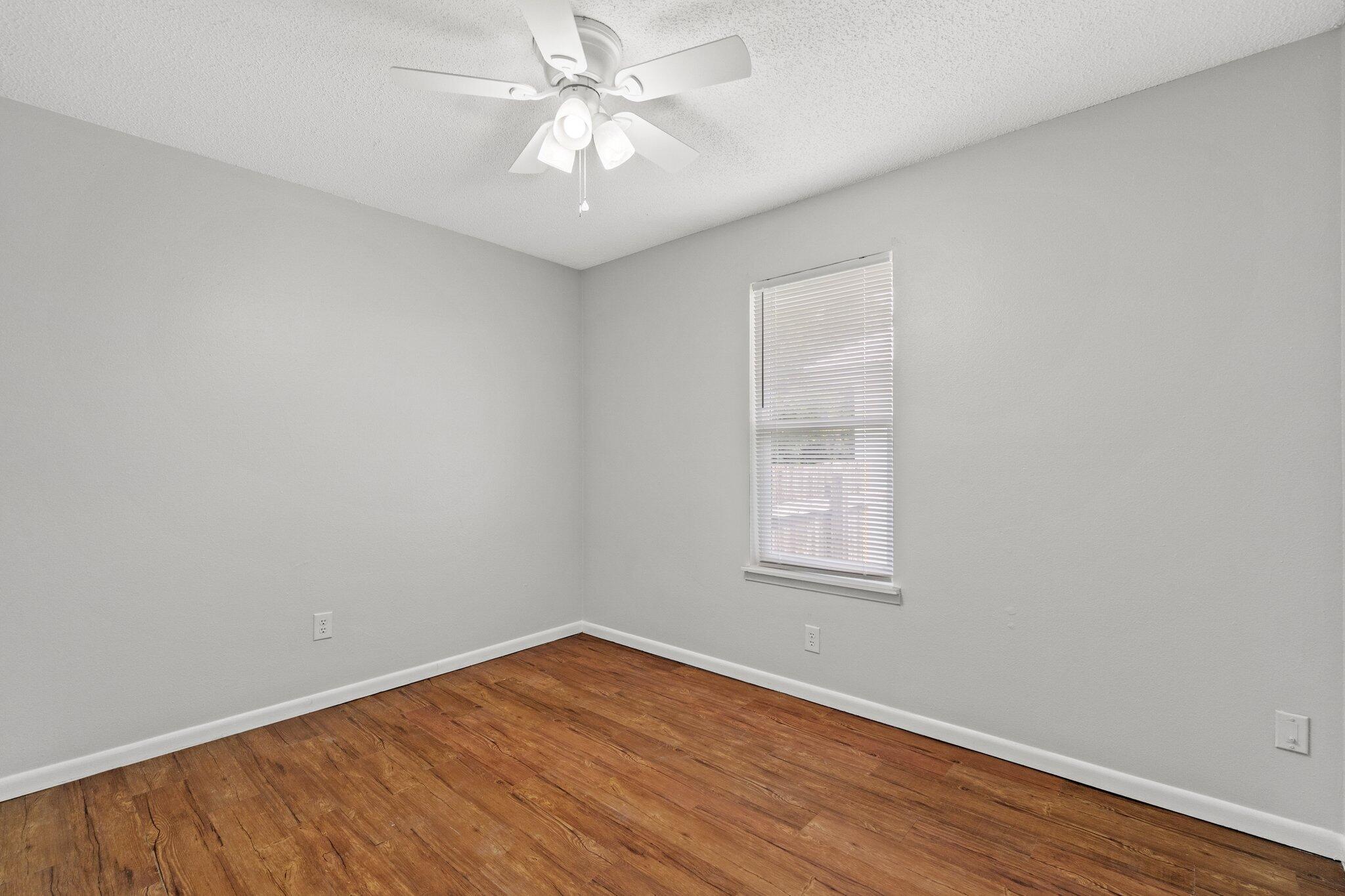 248 4 Mile Road, Unit G Freeport, FL 32439 - Photo 14 of 19 an empty room with wooden floor window and ceiling fan