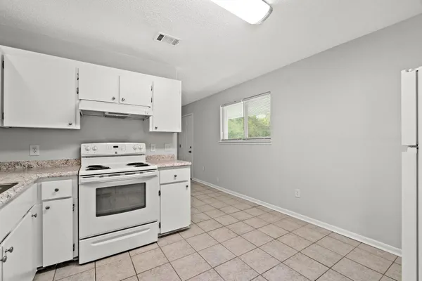 a kitchen with granite countertop white cabinets and white appliances