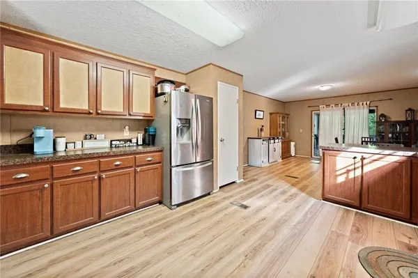 a kitchen with stainless steel appliances granite countertop a refrigerator a sink dishwasher a stove and white countertops with wooden floor