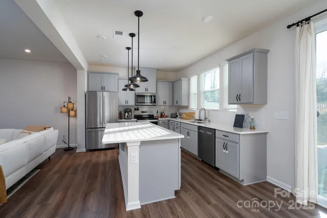 a kitchen with stainless steel appliances kitchen island a hardwood floor sink stove and wooden floor