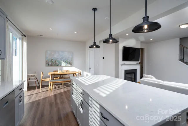 a kitchen with stainless steel appliances a stove a sink a dining table and chairs with wooden floor