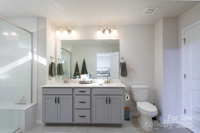 a bathroom with a double vanity sink toilet and a mirror