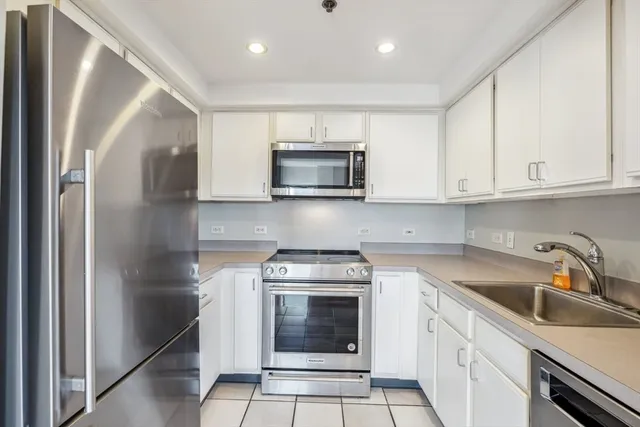 a kitchen with granite countertop white cabinets stainless steel appliances and a sink