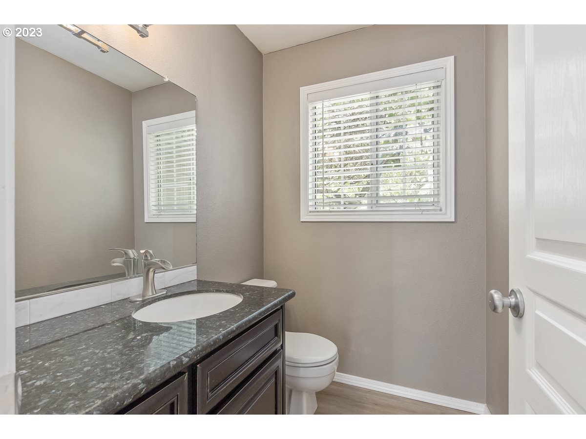 8580 Southwest Thoroughbred Place Beaverton, OR 97008 - Photo 14 of 43 a bathroom with a granite countertop sink toilet a mirror and a window