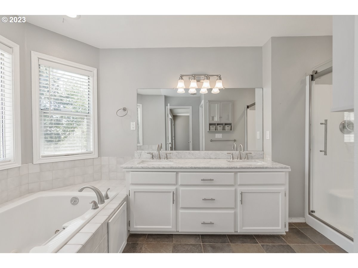 8580 Southwest Thoroughbred Place Beaverton, OR 97008 - Photo 23 of 43 a spacious bathroom with a granite countertop sink a mirror a bathtub and shower