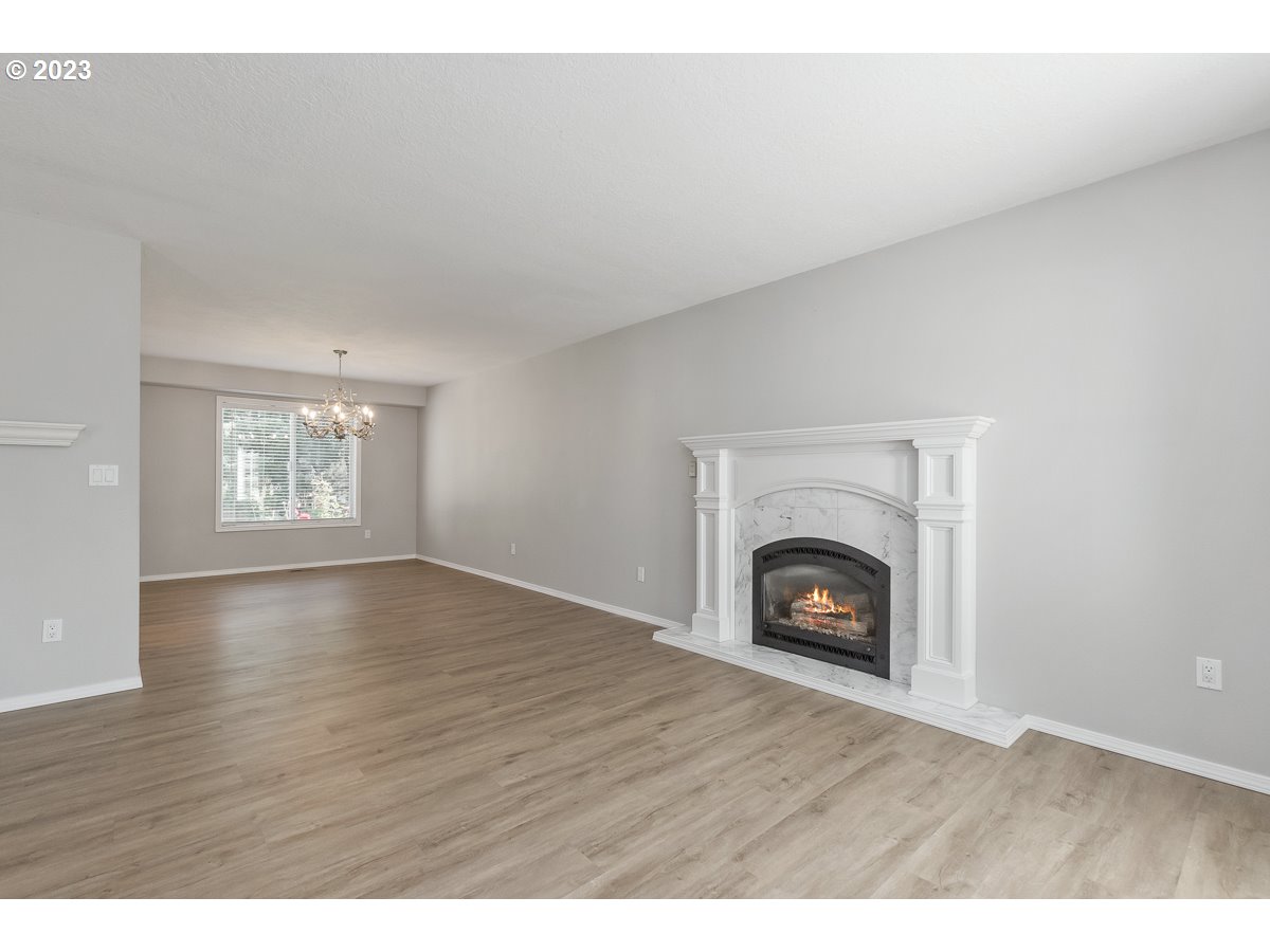 8580 Southwest Thoroughbred Place Beaverton, OR 97008 - Photo 4 of 43 a view of an empty room with wooden floor fireplace and a window