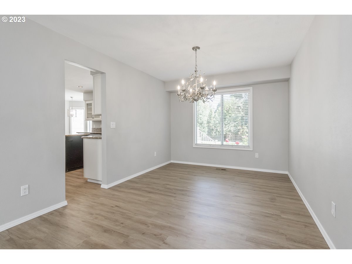 8580 Southwest Thoroughbred Place Beaverton, OR 97008 - Photo 6 of 43 an empty room with wooden floor chandelier and windows