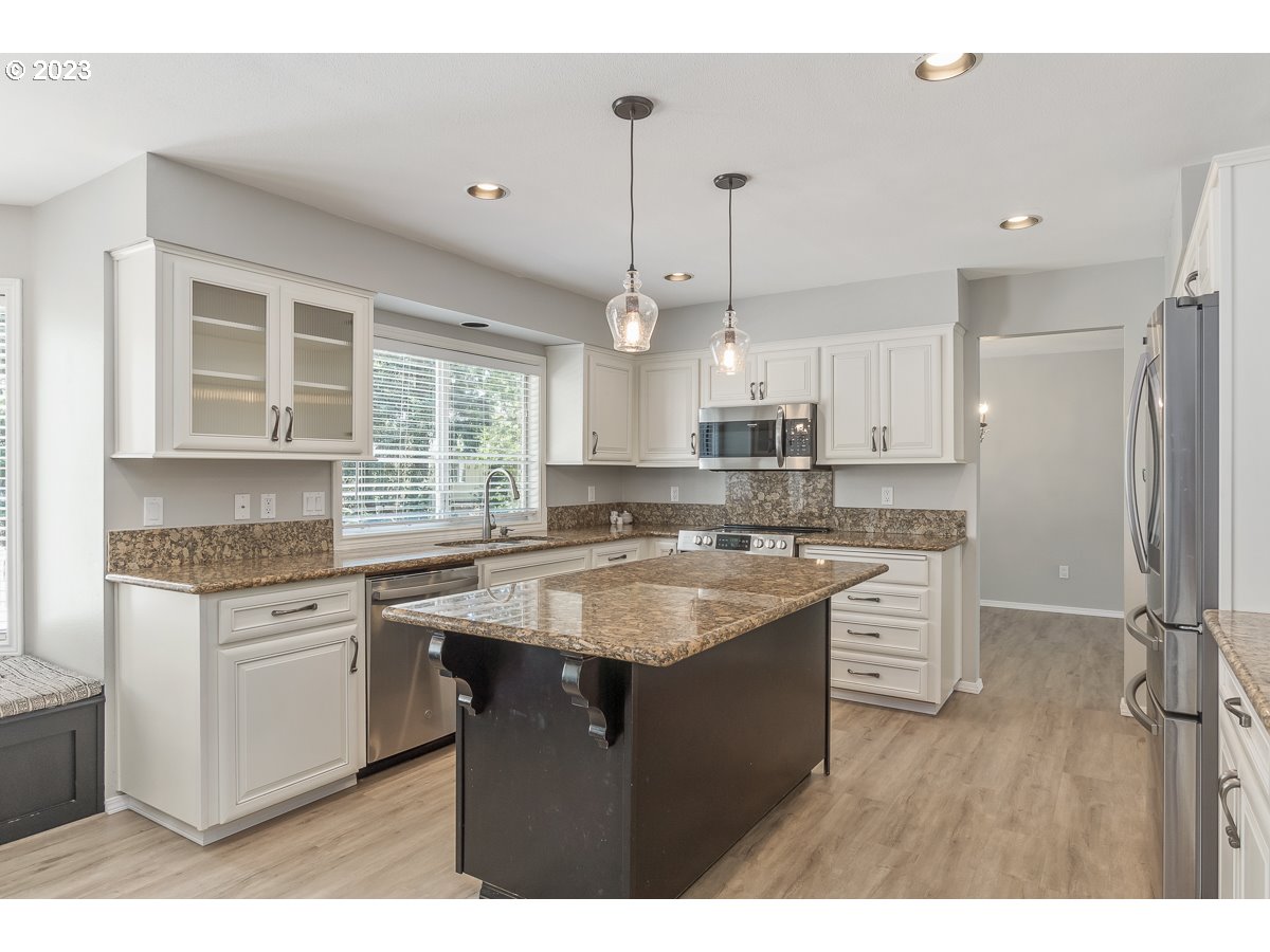 8580 Southwest Thoroughbred Place Beaverton, OR 97008 - Photo 8 of 43 a kitchen with kitchen island granite countertop a sink appliances cabinets and a counter top space