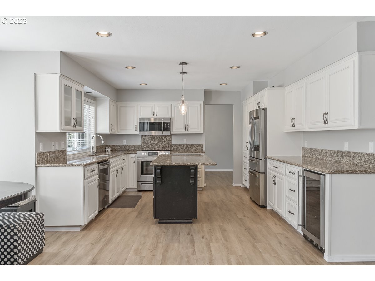 8580 Southwest Thoroughbred Place Beaverton, OR 97008 - Photo 9 of 43 a kitchen with stainless steel appliances granite countertop a refrigerator a sink dishwasher a stove and white countertops with wooden floor