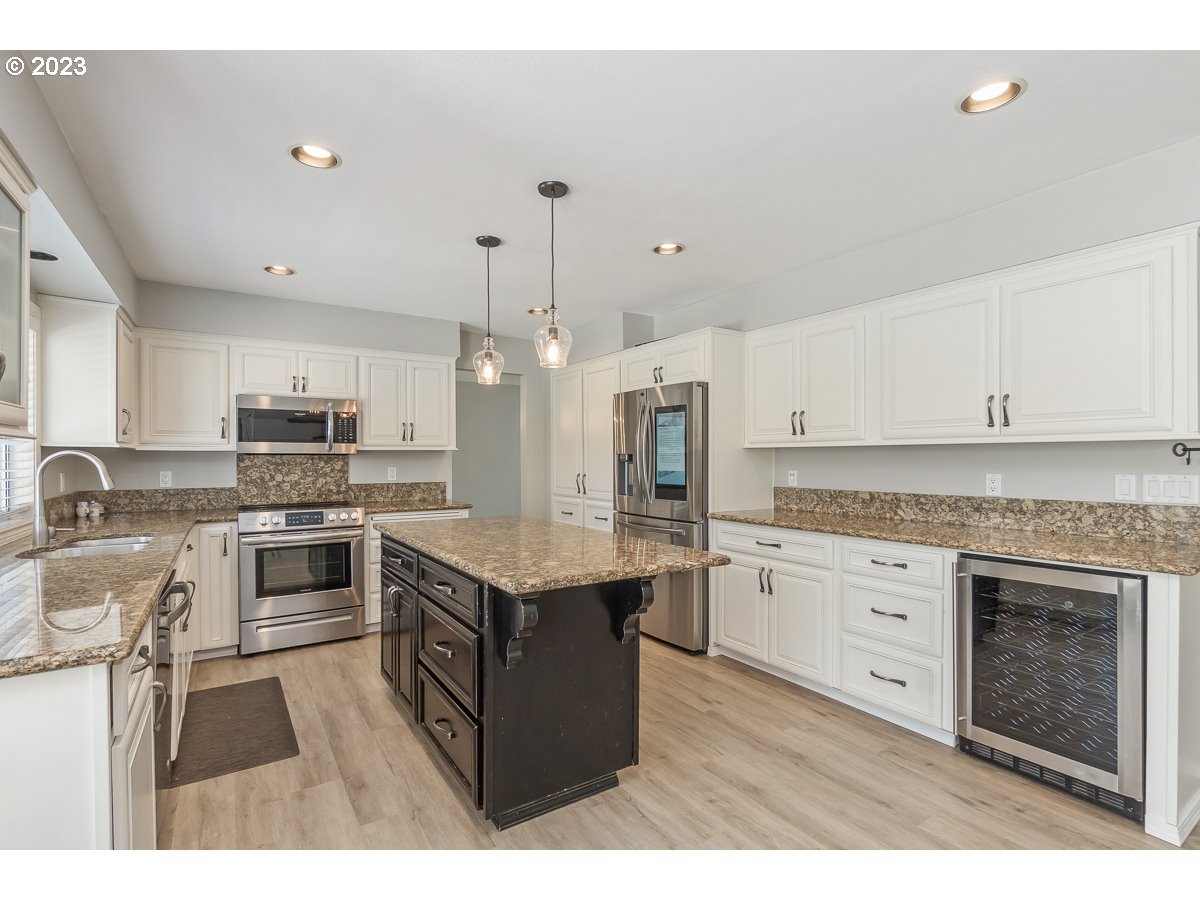 8580 Southwest Thoroughbred Place Beaverton, OR 97008 - Photo 10 of 43 a kitchen with stainless steel appliances granite countertop a stove top oven a sink dishwasher a refrigerator and a dining table with wooden floor