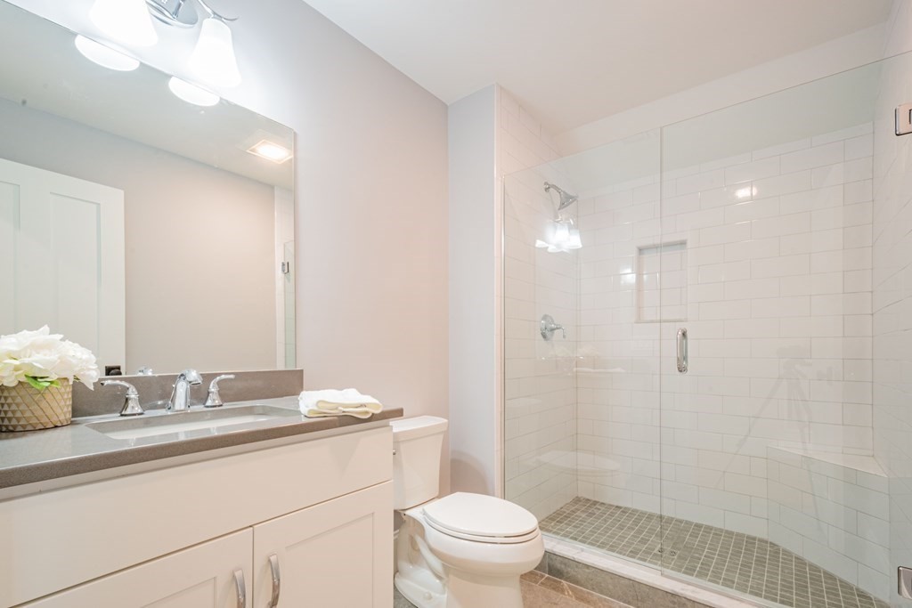 18 Pine Knoll Road Lexington, MA 02420 - Photo 37 of 42 a bathroom with a granite countertop sink toilet a large mirror a shower and a mirror