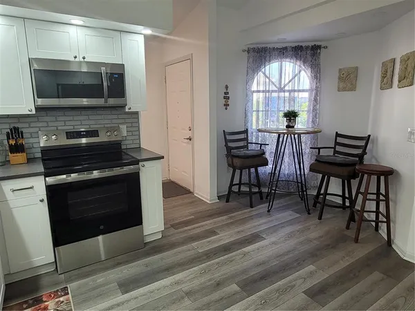 a kitchen with a table chairs microwave and window