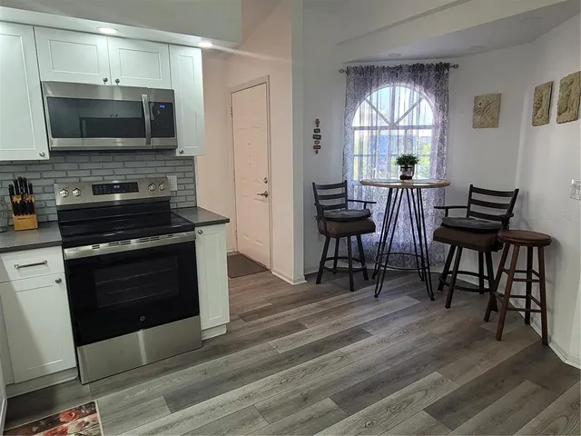 a kitchen with a table chairs microwave and window
