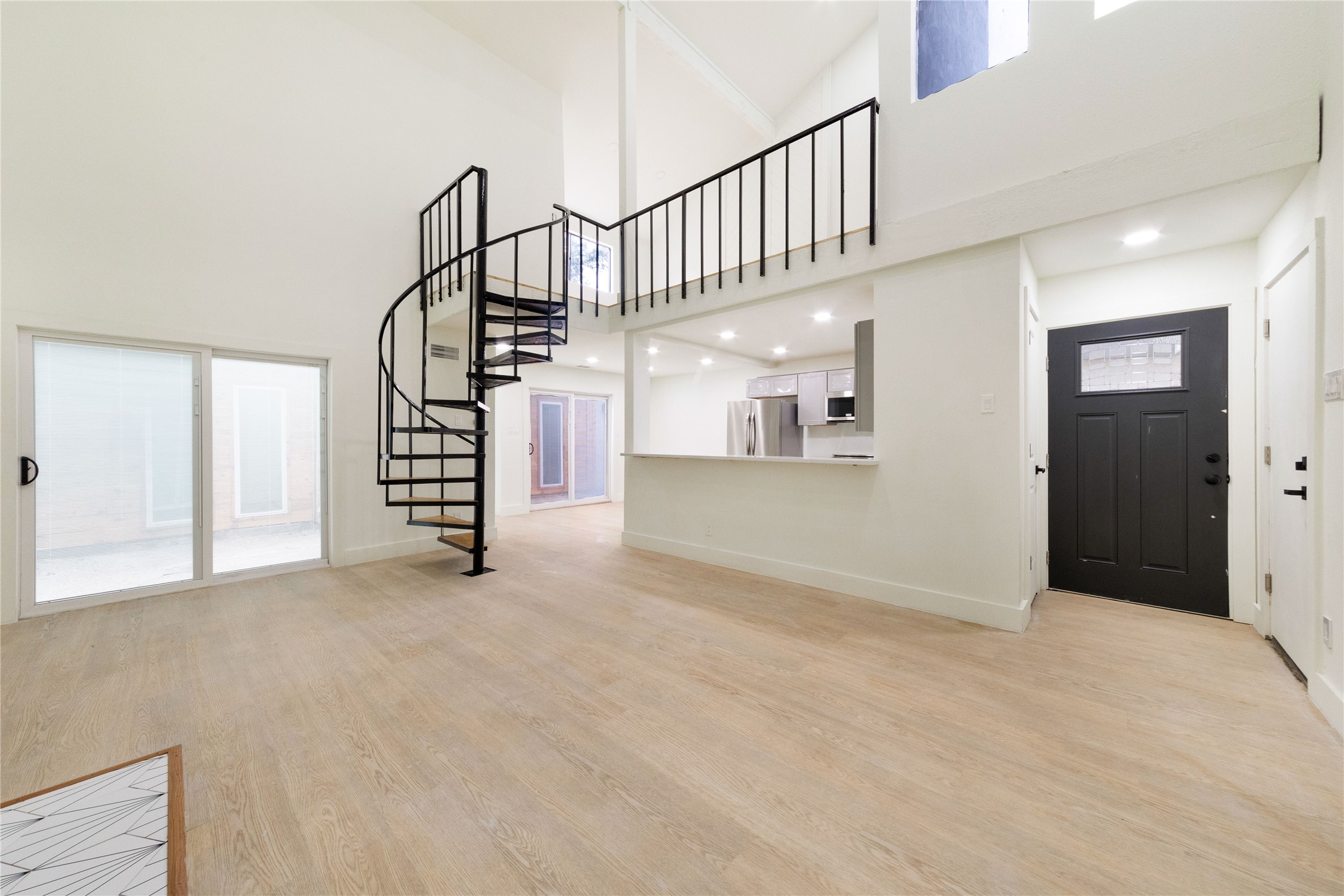 8807 Merion Circle Austin, TX 78754 - Photo 2 of 18 A striking spiral staircase elevates this open-concept interior with vaulted ceilings and a modern kitchen.
