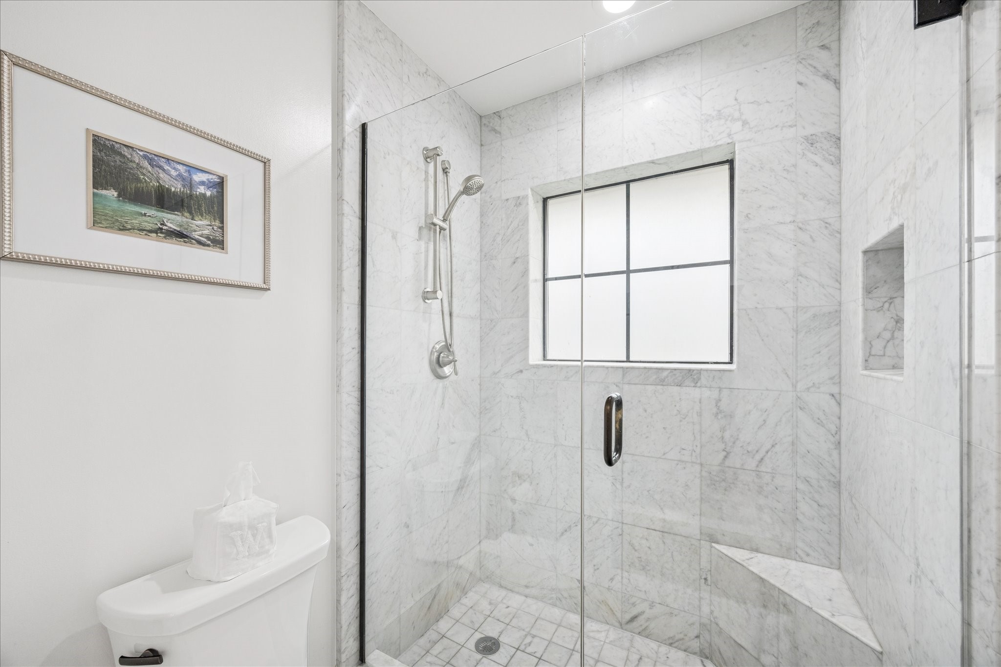 7906 Meadowbriar Lane Houston, TX 77063 - Photo 22 of 34 The private space for shower and toilet in the primary bathroom. Floor to ceiling marble and glass shower surround with natural light from the frosted window brings light to your daily routine.