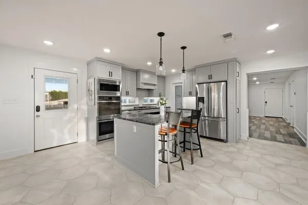 a kitchen with stainless steel appliances kitchen island granite countertop a refrigerator and a stove top oven