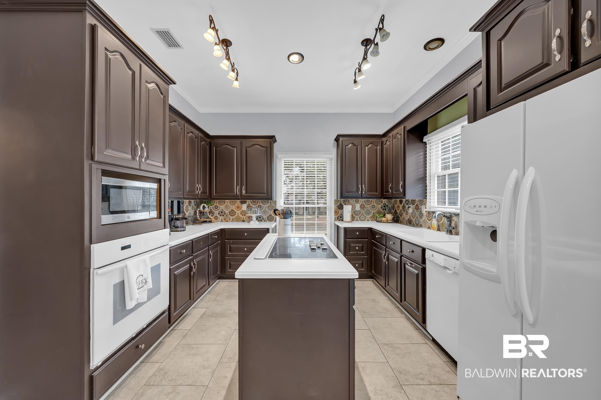 2858 Postoak Circle Mobile, AL 36693 - Photo 17 of 32 Kitchen featuring white appliances, dark brown cabinetry, a kitchen island, crown molding, and light countertops