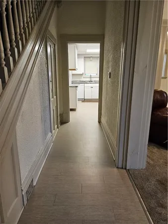a view of a hallway to a livingroom with wooden floor and windows