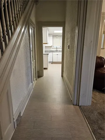 a view of a hallway to a livingroom with wooden floor and windows