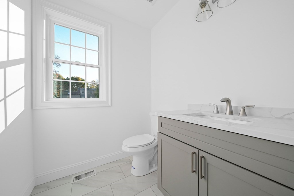 1 Northway Road Randolph, MA 02368 - Photo 15 of 40 a bathroom with a granite countertop toilet a sink a mirror and a window