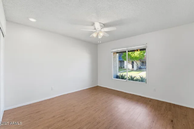 an empty room with a window and a ceiling fan